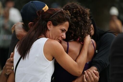 People hug outside the Bondi Pavillion in Sydney, where flowers have been laid in memory of the victims of a mass shooting.