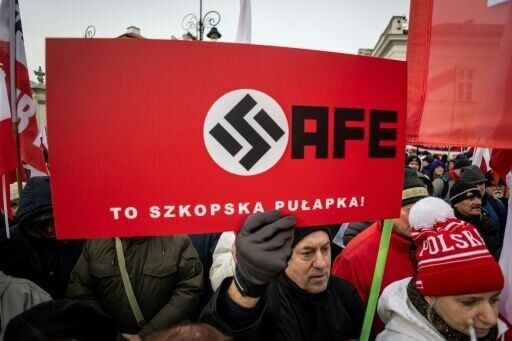 A supporter of Polish president Karol Nawrocki holding a poster claiming that the SAFE EU defence loans are a Nazi 'German trap'