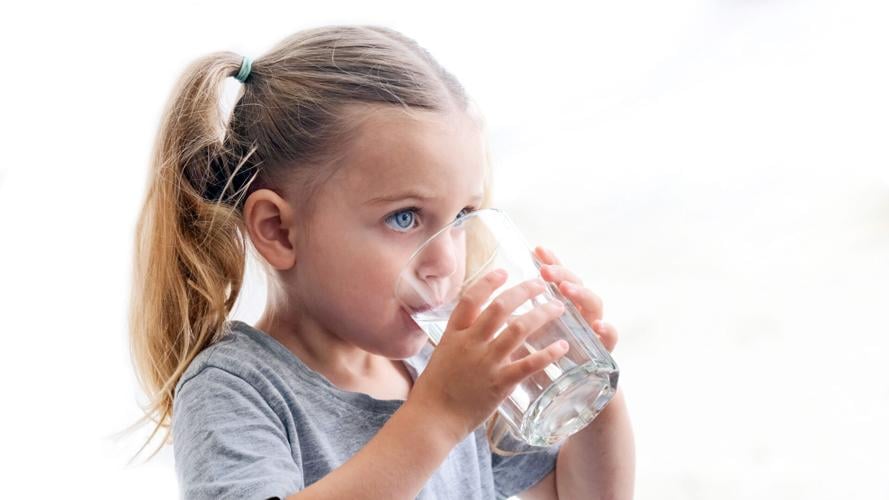 Child girl drinks water silhouette window background