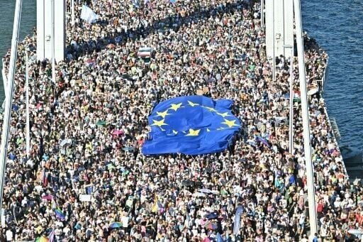 People taking part in Budapest Pride hold an EU flag as they cross a bridge over the Danube