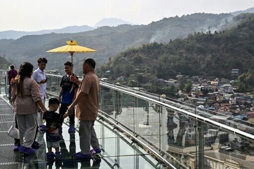 Smoke can be seen from brush fires on hills in Tachileik, Myanmar, as visitors walk on a skybridge at Wat Phra That Doi Wao Buddhist temple in Mae Sai in the northern Thai province of Chiang Rai