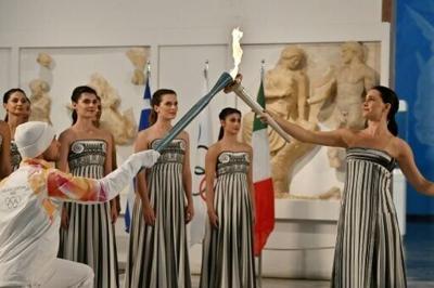 Greek actress Mary Mina (R), playing the role of the High Priestess, passed the Olympic flame to Greek rower Petros Gaidatzis