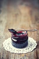 Jar of jam with spoon on old wooden table. Retro toned.