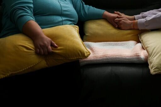 Ana (L) holds hands with a friend inside her home