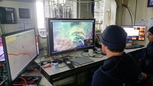 Scientists aboard the Alkor research vessel look at footage of munition on the seabed