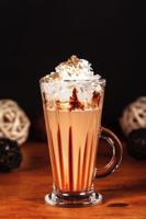 Beautifully designed latte macchiato coffee with whipped cream, in a high transparent glass, on a dark background