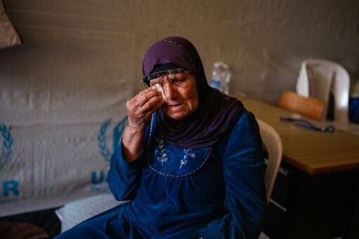 An elderly displaced woman reacts as she sits in her room at a school being used as a shelter for displaced people in the southern Lebanese city of Tyre