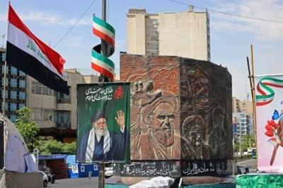Commuters make their way past a picture of Iran's slain supreme leader Ayatollah Ali Khamenei (L) and a sculpture of late supreme leader Ayatollah Ruhollah Khomeini in Tehran