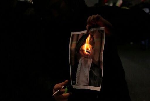 A protestor in London burns an image of Iran's spiritual leader Ayatollah Ali Khamenei at a rally in support of demonstrators in Iran