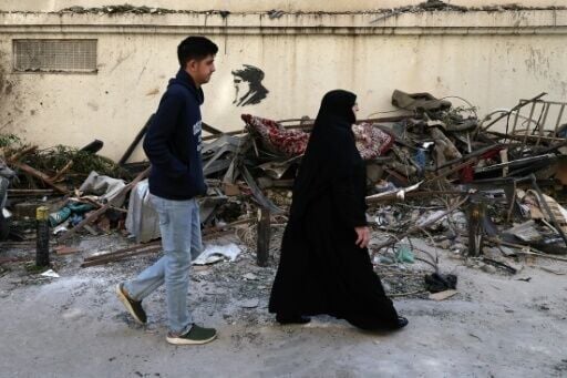 Residents walk past scattered debris at the site of an Israeli airstrike in the Lebanese capital Beirut