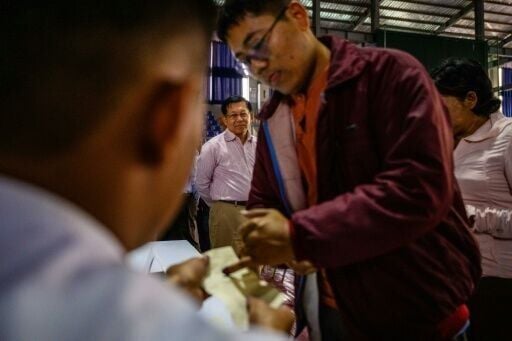 Military chief Min Aung Hlaing (back C) watches a voter ink their finger as he visits a polling station during the final phase of Myanmar's general election in January