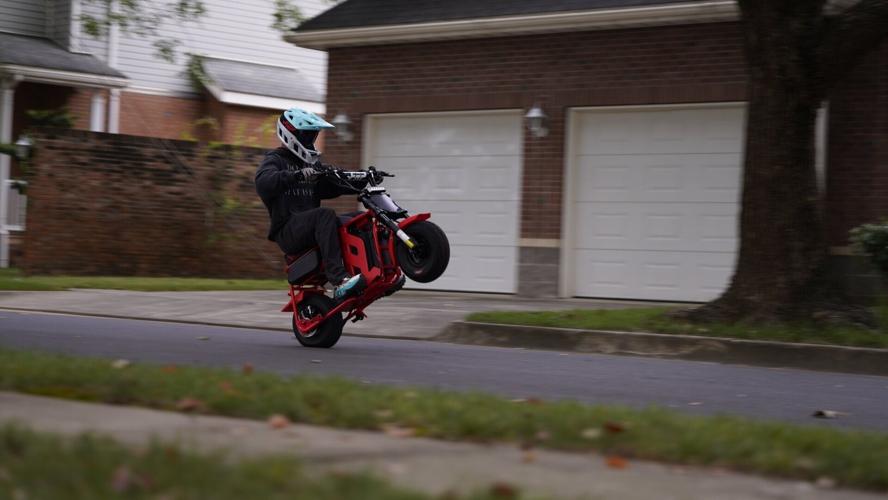 A rider lifts the front wheel on the FRP M3 electric mini bike, which offers dedicated practice and advanced wheelie modes
