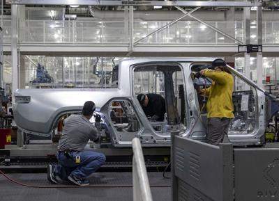Workers assemble R1T trucks Monday, April 11, 2022, at the Rivian electric vehicle plant in Normal, Illinois.