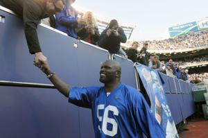 New York Giants legend Lawrence Taylor shakes hands of Giants fans after being introduced at halftime of the Sunday's 41-9 loss