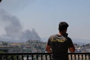 Civil defense member stands as smoke billows from southern Lebanon, as seen from Nabatieh
