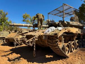 An Israeli soldier works on a tank on the Israeli side of the Israel-Lebanon border