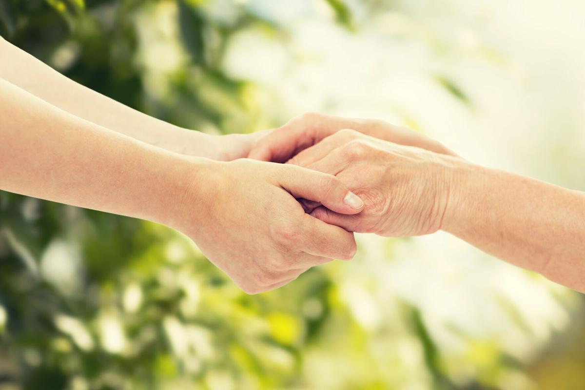 close up of senior and young woman holding hands