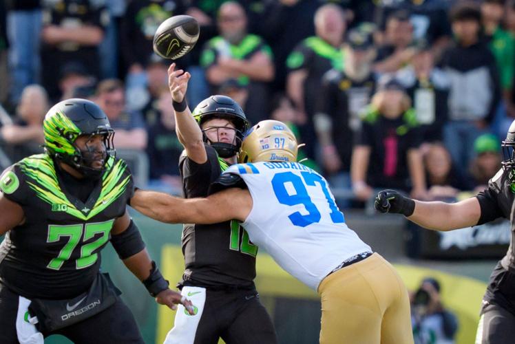 Oregon quarterback Brock Thomas throws a pass as he is hit by UCLA defensive lineman Aiden Gobaira as the Oregon Ducks host the