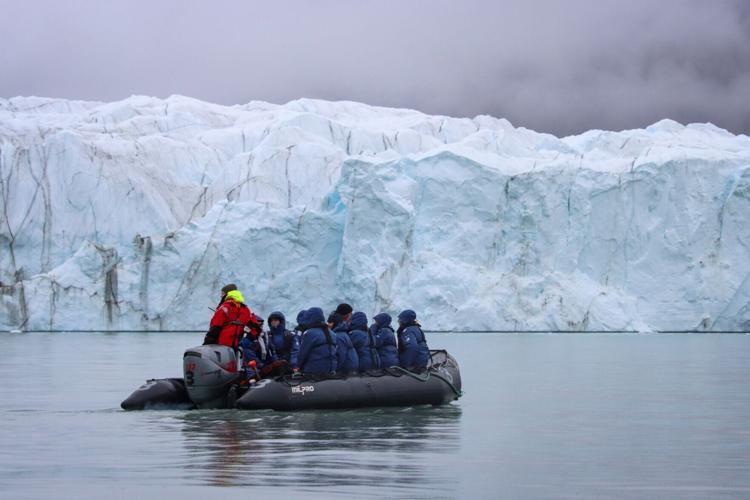 Guests hop into a dingy to reach land from the expedition ship off Greenland.