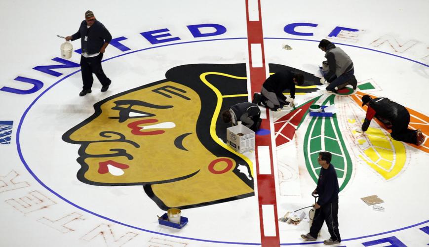 Workers paint the Blackhawks logo at the United Center.