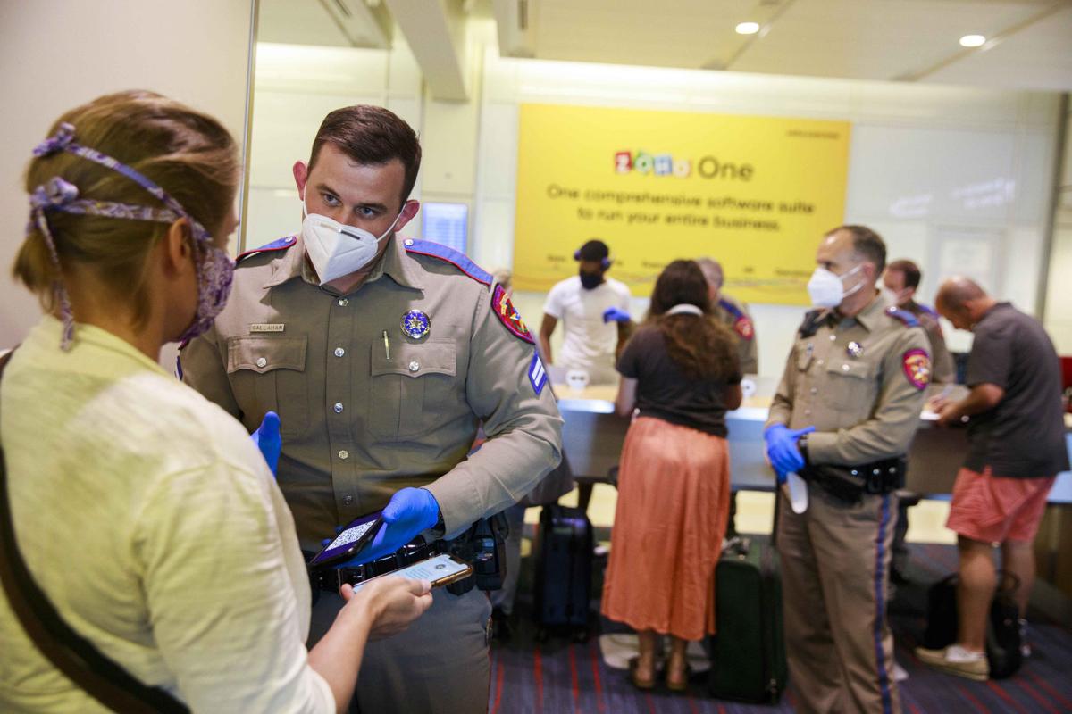 Police officers wear face masks as a preventive measure while verifying the identification of passengers arriving at an American Airlines flight in Texas on May 6, 2020, in Dallas.