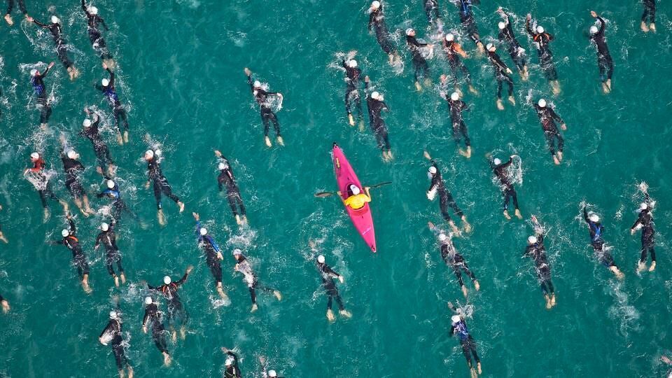 A kayaker paddles among swimmers