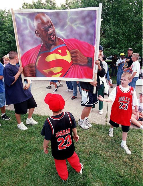 Carlos Medina, left, and friend Alfonso Carrazco carry a painting of Michael Jordan as Superman to the amusement and interest of all who see at as they wander through the Bulls' victory rally crowd at Grant Park on June 16, 1998. Carlos' father painted the piece.