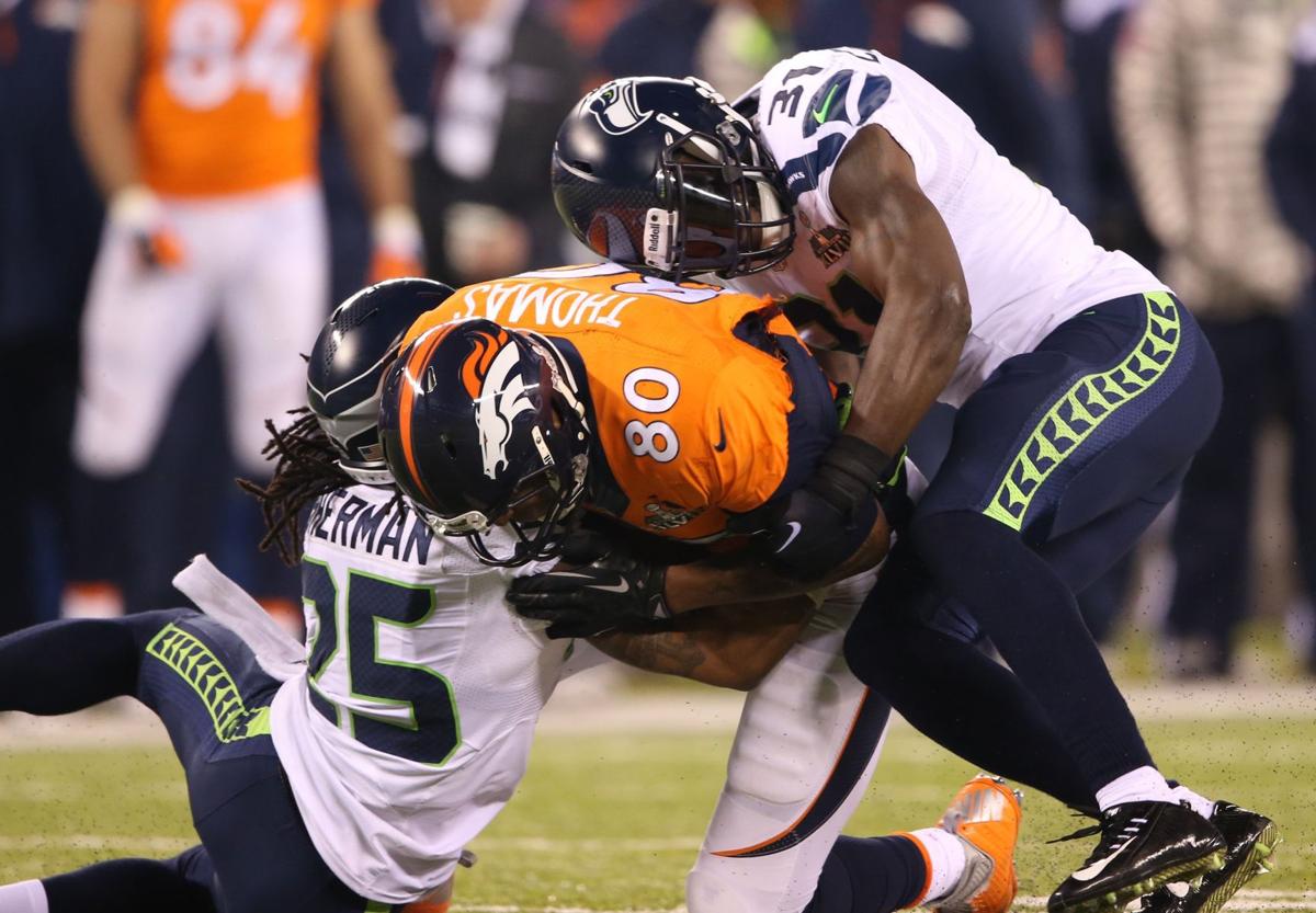 Julius Thomas (80) of the Denver Broncos is hit by Richard Sherman (25) and Kam Chancellor (31) of the Seattle Seahawks during Super Bowl XLVIII at MetLife Stadium in East Rutherford, N.J., on February 2, 2014.