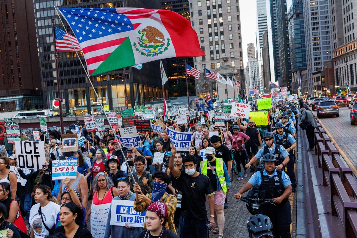 People walk along North Michigan Avenue in Chicago, while protesting President Donald Trump and recent immigration enforcement actions by federal officers in the area, Sept. 30, 2025.