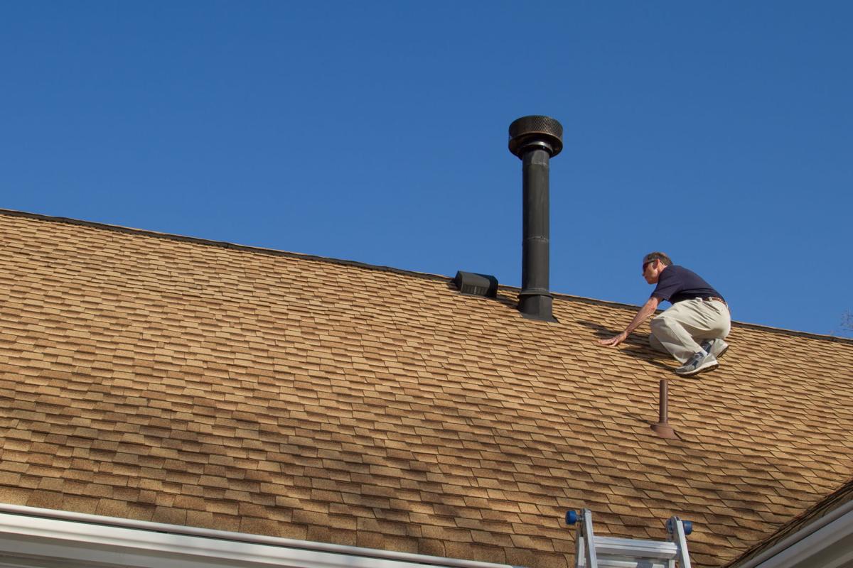 Home Inspector, on the roof, examines a roof gas vent.