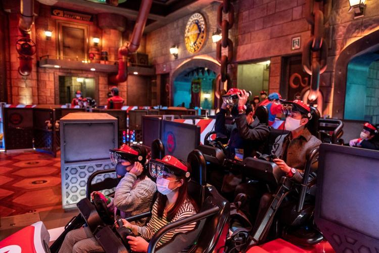 Universal Studios Japan visitors wear themed augmented reality goggles for the "Mario Kart" ride during a media preview of the Super Nintendo World at Universal Studios Japan in Osaka on March 17, 2021.