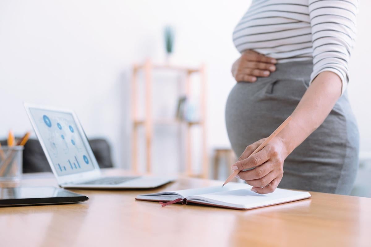 Pregnant woman at work writing in binder