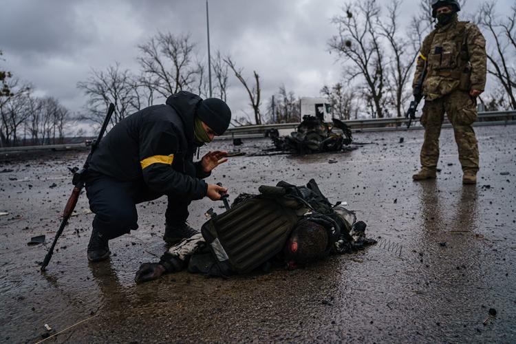 *EDITOR'S NOTE: GRAPHIC CONTENT* Ukrainian soldiers salvage equipment off a body of a dead Russian soldier after a Russian vehicle was violently destroyed Ukrainian forces in battle along the main road near Sytnyaky, Ukraine, Thursday, March 3, 2022.