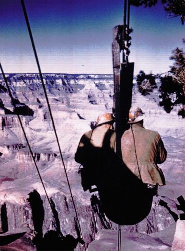 Workers riding an ore bucket over the Grand Canyon