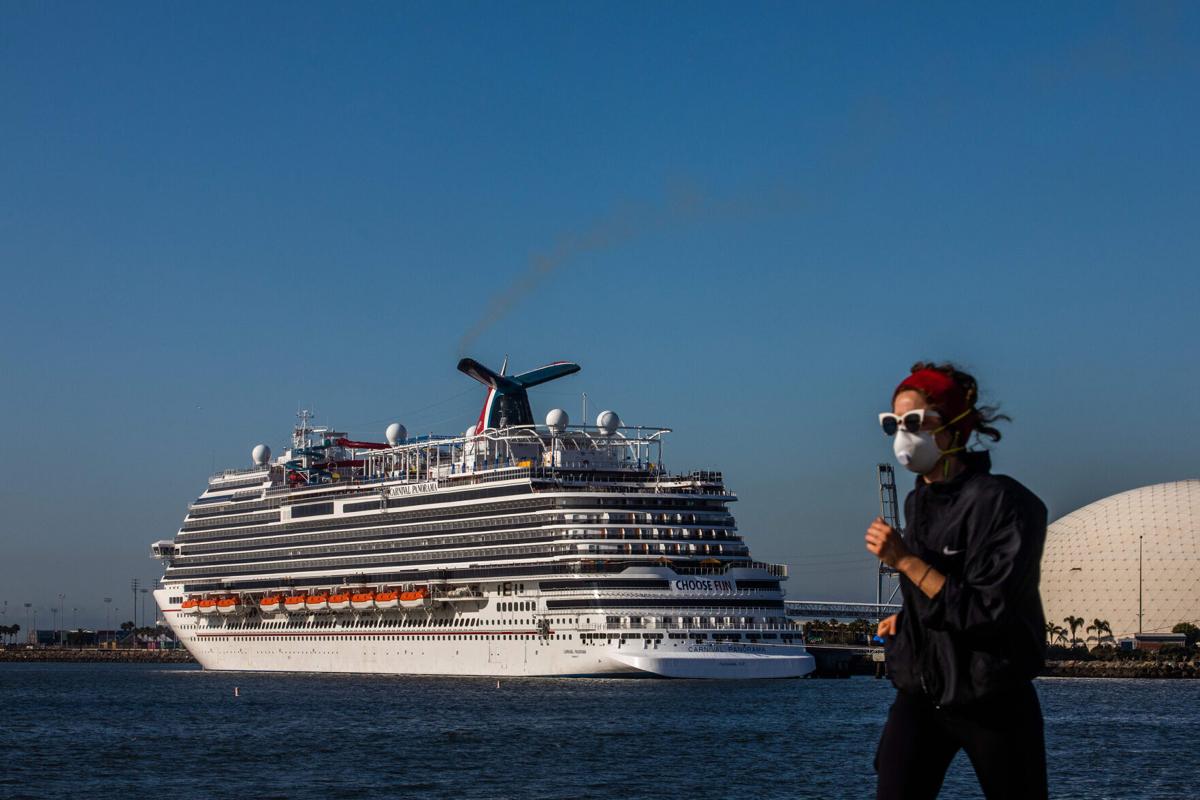 In this photo from April 11, 2020, a woman wearing a face mask as a preventive measure against the spread of coronavirus runs with Cruise Ships docked in the background due to a no-sail order at the port of Long Beach, California.