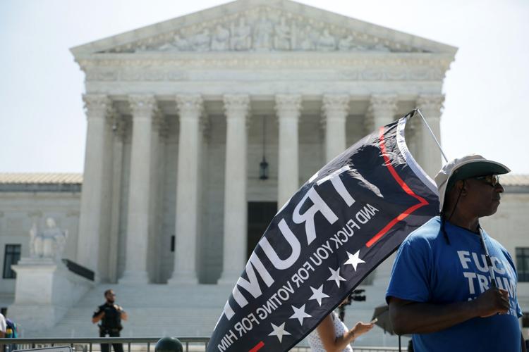 A man carries a flag in front of the U.S. Supreme Court on June 30, 2026, in Washington, D.C. Today, the U.S. Supreme Court struck down a ban on birthright citizenship, upheld state restrictions on transgender athletes in female sports and eliminated federal limits on coordinated campaign spending.