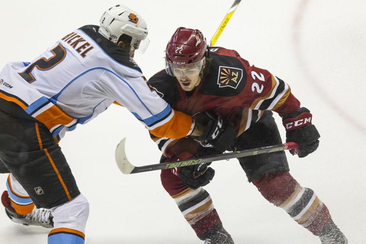 Tucson Roadrunners right wing Conor Garland pushes against San Diego Gulls right wing Stu Bickel while contesting for control of the puck.