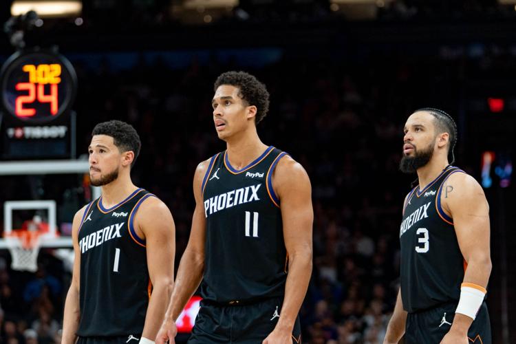 Phoenix Suns guard Devin Booker (1), forward Oso Ighodaro (11) and guard Dillon Brooks (3) watch as the Dallas Mavericks attempt a free throw during a game at Mortgage Matchup Center in Phoenix on Feb. 10, 2026.