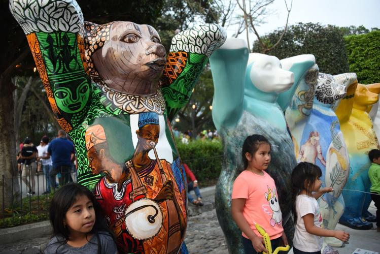 Guatemalans visit the itinerant exhibition "United Buddy Bears, The Art of Tolerance" at the Plaza Mayor Antigua Guatemala, 45 km West of Guatemala City on April 28,2019. - Each of the 144 two-meter-high colorful bears represents a UN member country.