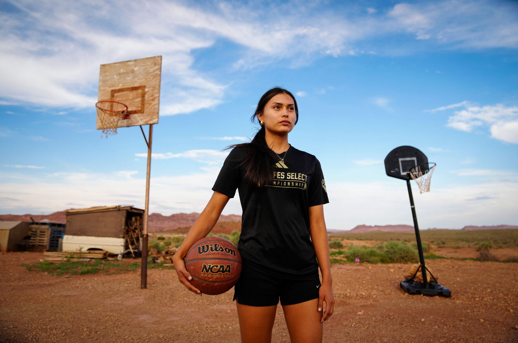 Layla Curtis poses for a picture at her home in The Gap on the Navajo reservation near Tuba City, Arizona, on Aug. 12, 2026. The hoop is the same one her father shot on as a Tuba City basketball star.