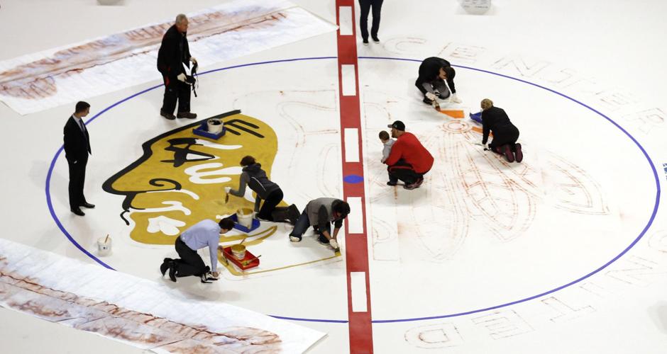 United Center staffers at center ice begin the annual ritual of painting the Blackhawks logo.