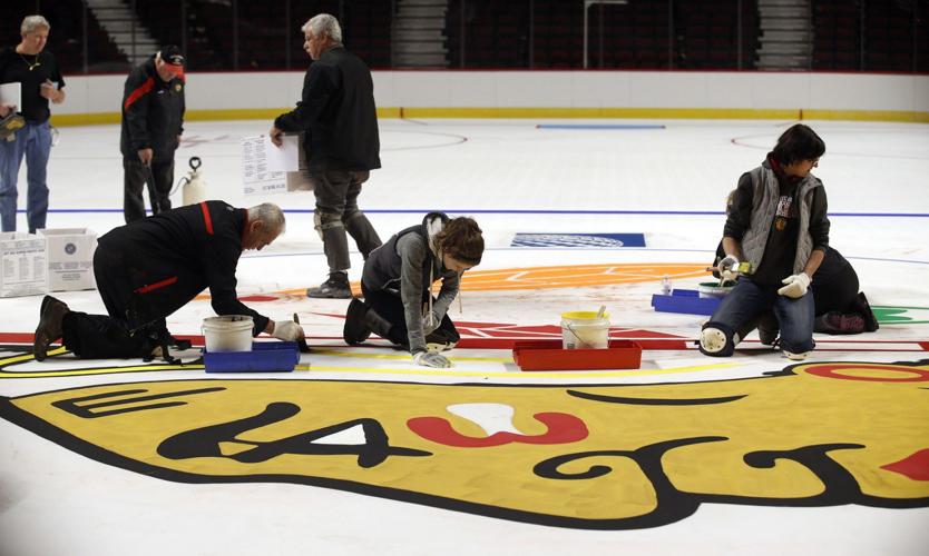 The Blackhawks logo is being painted onto the United Center ice.