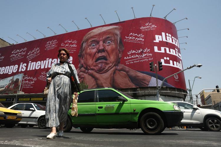 People walk near a billboard depicting U.S. President Donald Trump on a building in Tehran