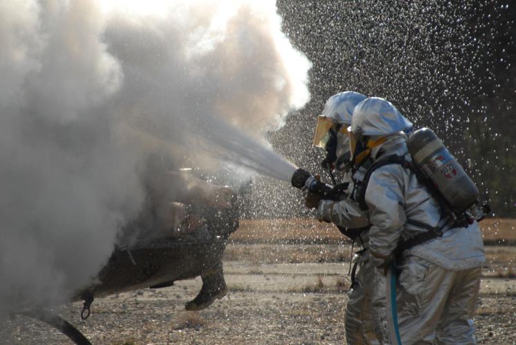Firefighters spray PFAS-laden foam to put out a helicopter fire during a training exercise in 2007. Firefighting foams form a "blanket" over liquid fuel that helps extinguish fires quickly. The Pentagon has extended its deadline to stop using the foam to O