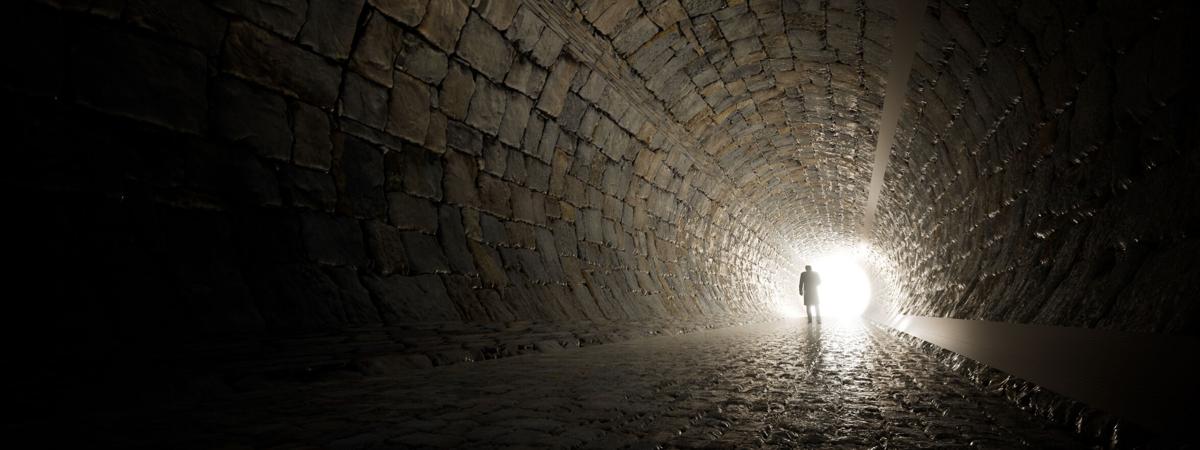 Concept or conceptual dark tunnel with a bright light at the end or exit as metaphor to success, faith, future or hope to new opportunity or freedom 3d illustration