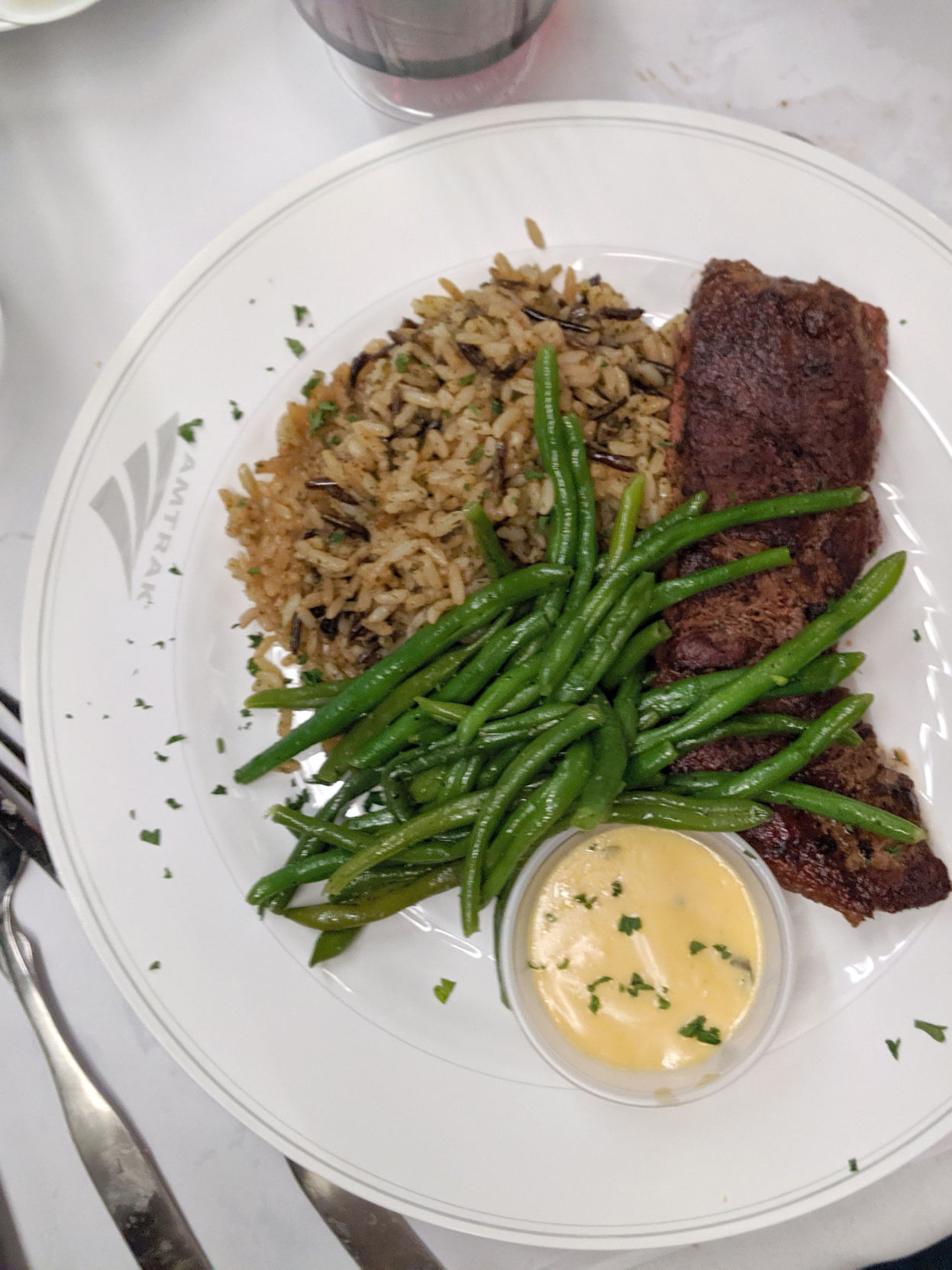 In the dining car, the Amtrak Signature Steak ($25) is grilled to order and served with bearnaise sauce, wild rice and green beans. Recommended pairing: a plastic half-bottle of cabernet sauvignon ($16).