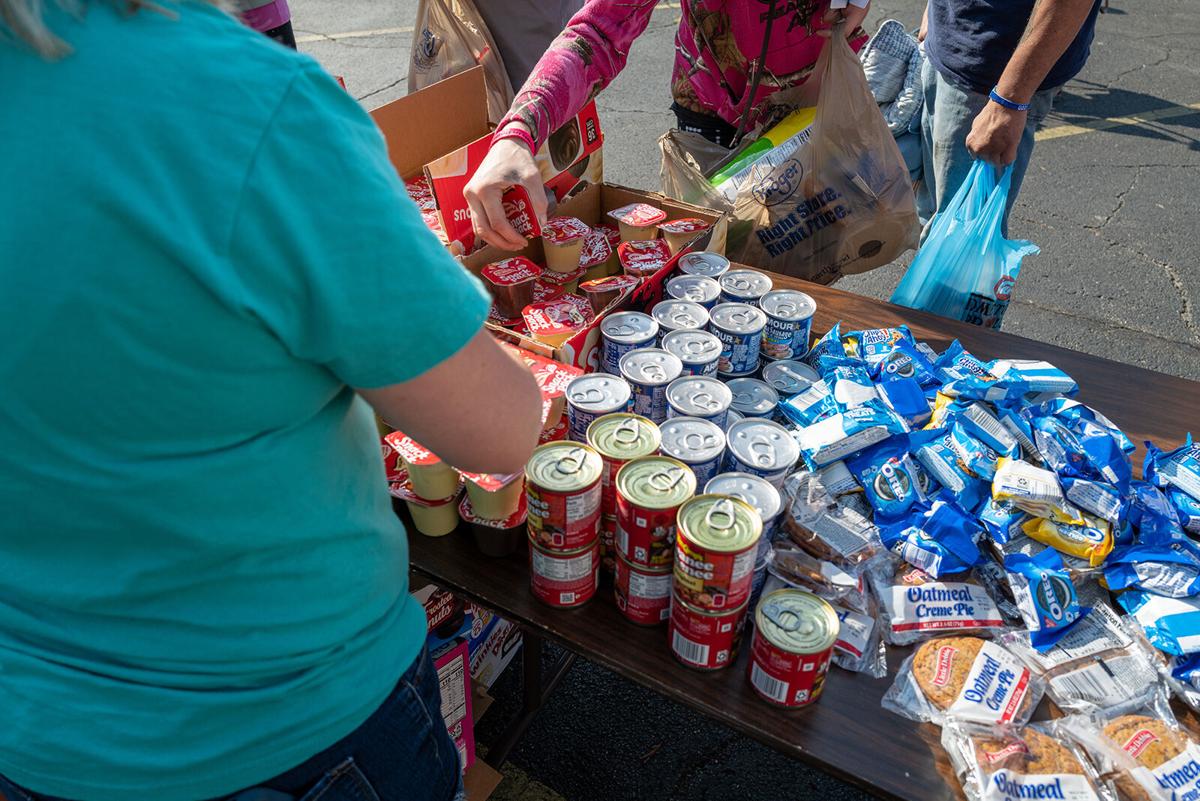 People line up for free food, groceries and clothing at the weekly Saturday River City Street Ministry food distribution on June 10, 2023, in Huntington, West Virginia. The weekly event, which is organized and run by a series of churches including religious motorcycle groups, has been operating for over 16 years in the economically stressed city.