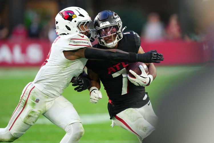 Atlanta Falcons running back Bijan Robinson (7) takes a hit from Arizona Cardinals safety Budda Baker (3) during the second half at State Farm Stadium in Glendale on Dec. 21, 2025.