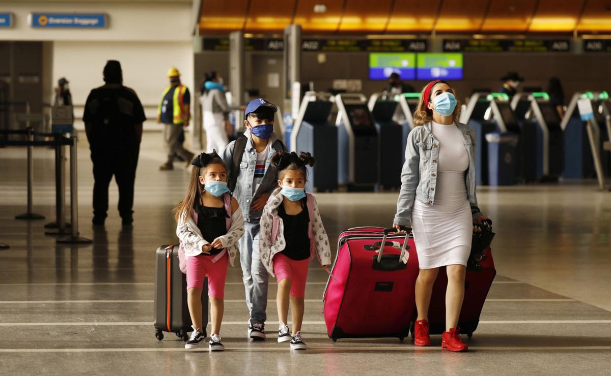 Yadira Barajas walks with her children Owen Vargas, 11, and 6-year-old twins Madison and Madelyn Contreras, as they prepare for a flight to Mexico at Tom Bradley International Terminal at Los Angeles International Airport, which is requiring travelers to wear face coverings to help keep fellow passengers and crew safe by limiting the spread of the coronavirus COVID-19, on May 11, 2020.