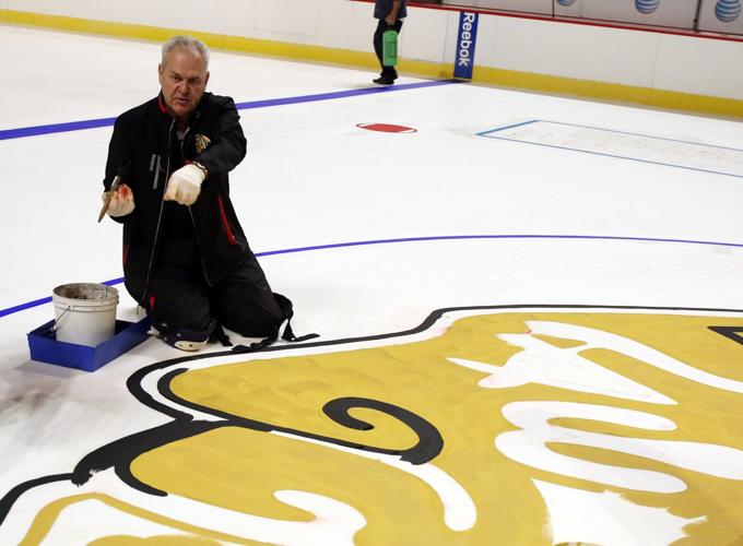 Jim Koehler, general manager of the United Center, works on the Blackhawks logo at center ice.
